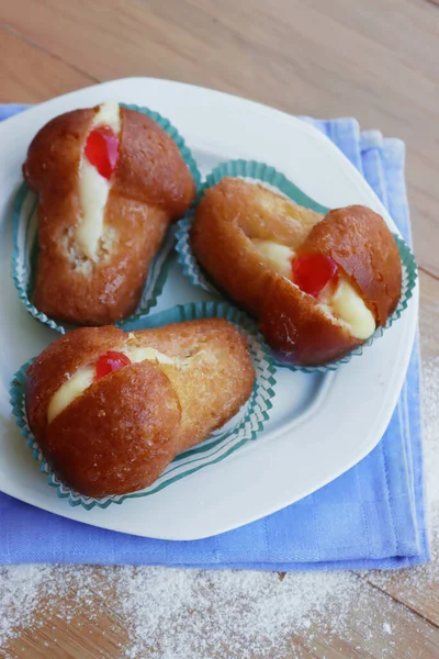 Geleneksel İtalyan tatlısının adı Bab with Rum. Tahta masadaki kremayla dolu. Napoli çöreği. 