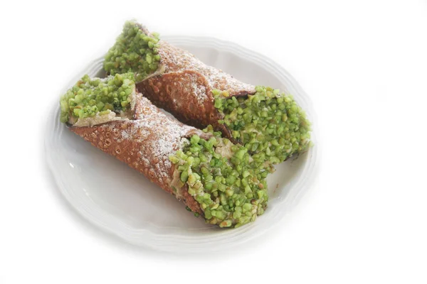 Beyaz bir tabakta yeşil şam fıstığı ve ricotta peyniri ile doldurulmuş tatlı İtalyan Cannoli hamur işleri.