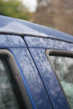 Mavi araba kış mevsiminde donla kaplı. Seçici odak noktasında arabanın yan görünümü.