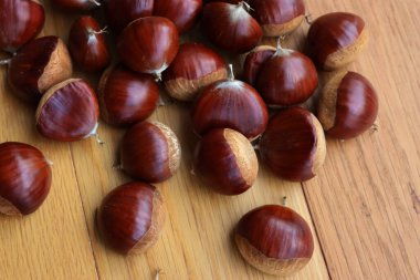 Pek çok olgun kestane, seçici odak üzerinde ahşap arka planda. Castanea sativa tohumları