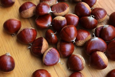 Pek çok olgun kestane, seçici odak üzerinde ahşap arka planda. Castanea sativa tohumları