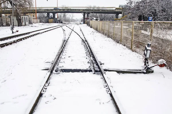 Railroad tracks and crossings at the train station covered by snow.