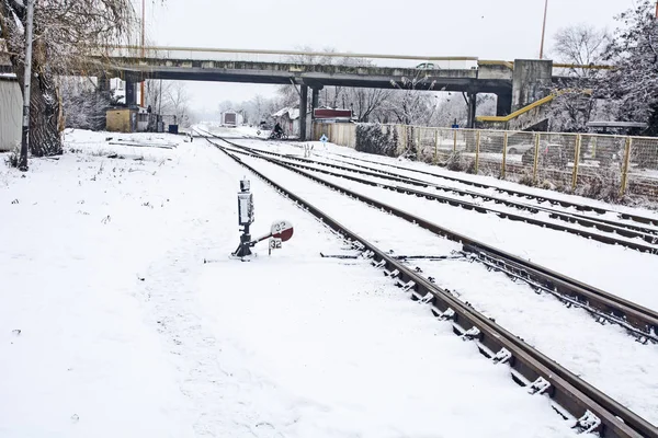 Railroad tracks and crossings at the train station covered by snow.