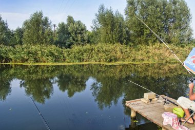 Spor balıkçı Tente altında bir platformda bir yakalamak için bekliyor.