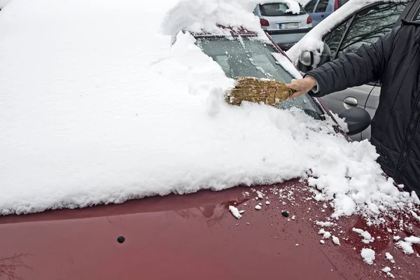 Водитель убирает снег с машины — стоковое фото