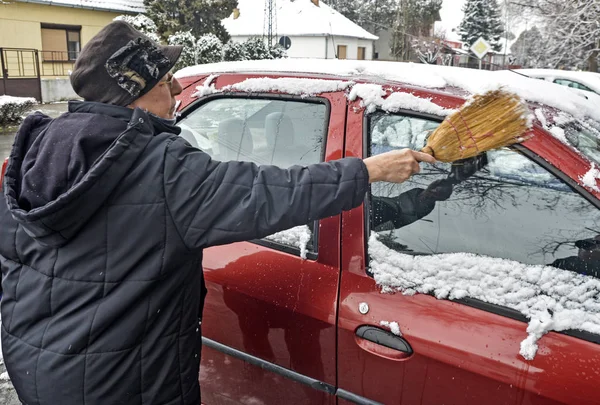 Женщина-водитель убирает снег с машины — стоковое фото
