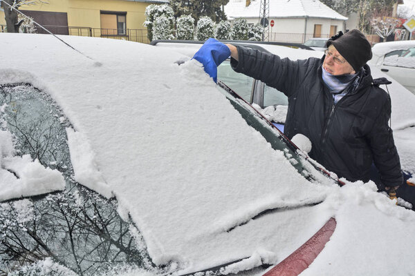 Driver cleaning snow from the windshield 