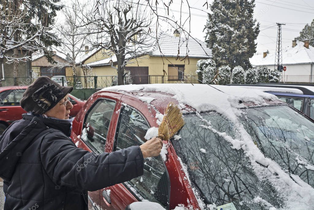 Driver cleaning snow from the windshield 