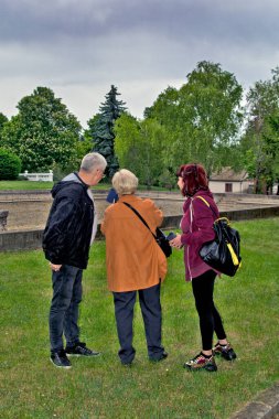 Kadınlar ve bir erkek parkta yürürler ve video bağlantısı kullanarak cep telefonlarıyla konuşurlar..