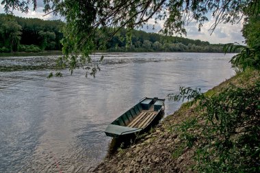Tisa Nehri ovanın içinden sessizce akar. Balıkçı teknesi kıyıya bağlandı ve balıkçıları bekliyor..