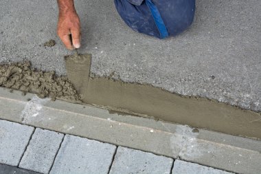 Usta kaldırım ve asfalt arasındaki boşluğu doldurur ve doldurur, bisiklet yolu gibi. Bunun için mala ve kum çimento kullanıyor..