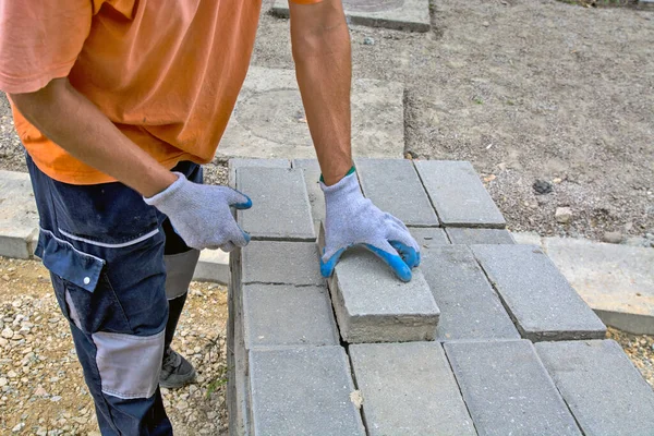 The master is laying new concrete bricks for the sidewalk on the pile. The bricks have been prepared for the laying of a new footpath.