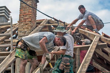 Zrenjanin, Sırbistan, 22 Temmuz 2020. Bir grup usta, eski bir fayans yerine özel bir evin çatısında çalışıyor. Güzel bir günü ve yağmursuz, istikrarlı bir havayı kullanıyorlar. Evin çatısından geçen çeşitli kablolar onları rahatsız ediyor..