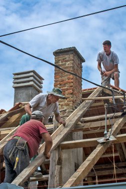 Zrenjanin, Sırbistan, 22 Temmuz 2020. Bir grup usta, eski bir fayans yerine özel bir evin çatısında çalışıyor. Güzel bir günü ve yağmursuz, istikrarlı bir havayı kullanıyorlar. Evin çatısından geçen çeşitli kablolar onları rahatsız ediyor..