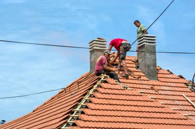 Zrenjanin, Sırbistan, 23 Temmuz 2020. Bir grup usta, eski bir fayans yerine özel bir evin çatısında çalışıyor. Güzel bir günü ve yağmursuz, istikrarlı bir havayı kullanıyorlar. Evin çatısından geçen çeşitli kablolar onları rahatsız ediyor..