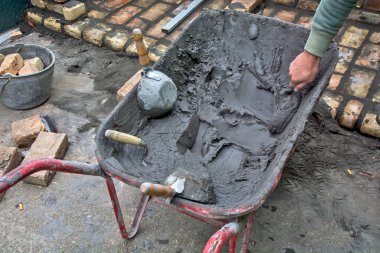 Binayı inşa etmek için el arabası, havan topu ve araç gereç park ettim. Duvarcıların birkaçı el arabasından havan topu kullanıyor..