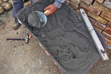 Binayı inşa etmek için el arabası, havan topu ve araç gereç park ettim. Duvarcıların birkaçı el arabasından havan topu kullanıyor..