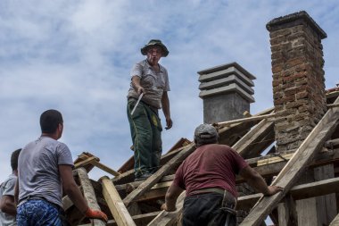 Zrenjanin, Sırbistan, 22 Temmuz 2020. Bir grup usta, eski bir fayans yerine özel bir evin çatısında çalışıyor. Güzel bir günü ve yağmursuz, istikrarlı bir havayı kullanıyorlar. Evin çatısından geçen çeşitli kablolar onları rahatsız ediyor..