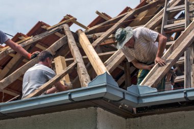 Zrenjanin, Sırbistan, 22 Temmuz 2020. Bir grup usta, eski bir fayans yerine özel bir evin çatısında çalışıyor. Güzel bir günü ve yağmursuz, istikrarlı bir havayı kullanıyorlar. Evin çatısından geçen çeşitli kablolar onları rahatsız ediyor..