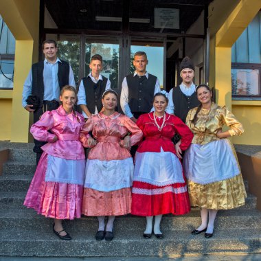 Ivanovo, Sırbistan, 15 Ağustos 2016. Folklor etkinliklerine katılan bir grup genç erkek ve kadın Kültür Evi önünde poz veriyor. Bulgar ulusal kostümleri giyiyorlar..
