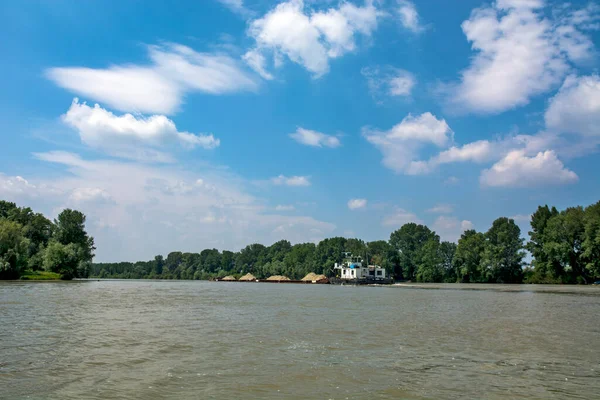 Novi Becej, Tisa Nehri, Sırbistan, 14 Mayıs 2017. Büyük ve güçlü bir nehir teknesi nehir boyunca kum ve çakıl yüklü mavnaları itiyor. Gemi nehrin ortasında güçlü bir şekilde ilerliyor..