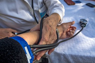 Doktor diyabet kontrolü sırasında hastanın kan basıncını ölçer..