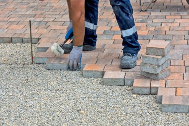 Usta halka açık bir zemine tuğla döşedi ve yerleştirdi. Taban küçük ve beton dekoratif tuğla parçalarına uyuyor..
