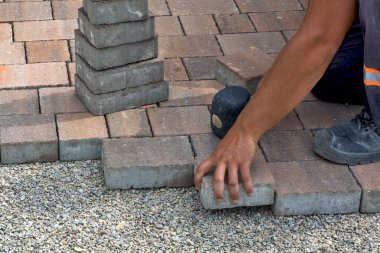 Usta halka açık bir zemine tuğla döşedi ve yerleştirdi. Taban küçük ve beton dekoratif tuğla parçalarına uyuyor..