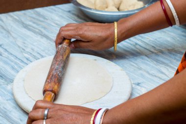 Hintli kadın tekerlek silindiriyle ekmek veya roti yapıyor..