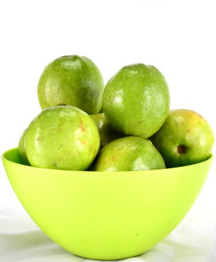 Bir grup taze seçilmiş Guava, yeşil bir kasede toplanmış, beyaz bir arka planda..