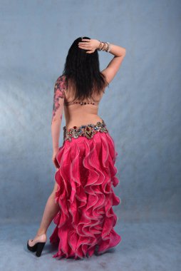 Oryantal elbiseli, duvak takmış, kırmızı etekli, göğüsleri mavi göğüslü güzel bir dansçı.