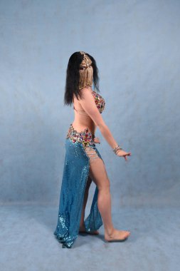 Oryantal elbiseli, duvak takmış, kırmızı etekli, göğüsleri mavi göğüslü güzel bir dansçı.