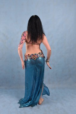 Oryantal elbiseli, duvak takmış, kırmızı etekli, göğüsleri mavi göğüslü güzel bir dansçı.