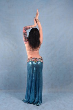 Oryantal elbiseli, duvak takmış, kırmızı etekli, göğüsleri mavi göğüslü güzel bir dansçı.