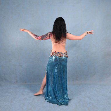 Oryantal elbiseli, duvak takmış, kırmızı etekli, göğüsleri mavi göğüslü güzel bir dansçı.