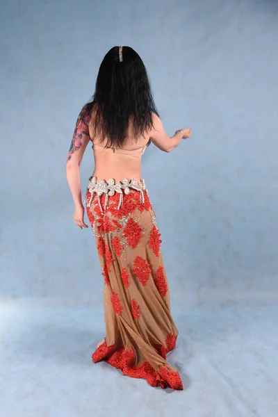 Красивая Танцовщица Цветочной Юбке Позирует Спиной Студии Голубом Фоне — стоковое фото