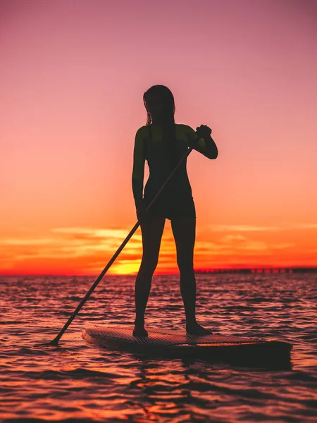 夕暮れ海でサーフボードに漕ぎサーフィン女性のシルエット — ストック写真