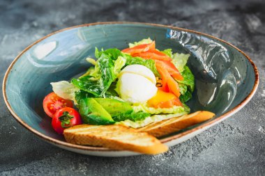 Sezar salatası sıcak yumurta, somon, avokado, domates ve vintage plaka, ızgara tost ile yakın çekim 