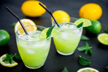 Kireç parçaları, nane yaprakları ve buz cam saman karanlık tablo ile taze limonata