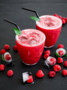 Ahududu buzla kokteyl, nane yaprakları ve saman karanlık tablo ile cam çilek