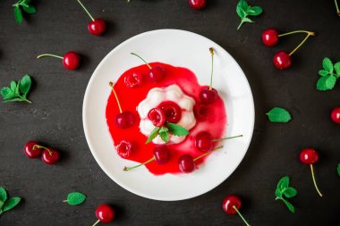üstünden biraz kiraz şurubu çilek ve nane yaprakları ile karanlık tabloda beyaz plaka ile panacota