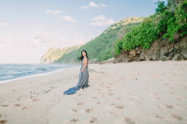 Gündoğumu veya günbatımı renkleri ile plajda mavi gelinlik gelin portresi.