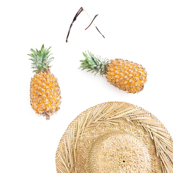 Top view of ripe pineapples and straw hat on white background