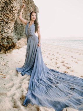 Gündoğumu renkleri, gün batımı ile plajda gri elbiseli kadın portresi.