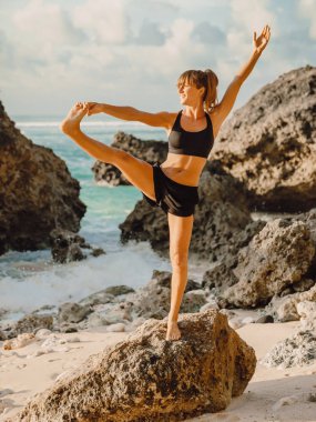 Gün batımında sahilde Yoga uygulamak genç sağlıklı kadın