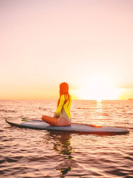 背景の島と海でサーフボードの上に座って美しいサーファー女性 — ストック写真
