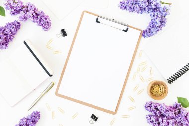 Boş bir kağıt yaprağına kliplerle ve defter taze leylak çiçekler ile üstten görünüm beyaz arka plan üzerinde