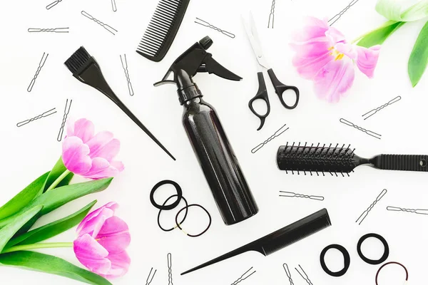 Hairdresser concept with spray, scissors, combs, barrette and tulips flowers on white background. Beauty concept. Flat lay, top view