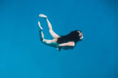 Su altında mavi okyanusta yüzen güzel çıplak kadın