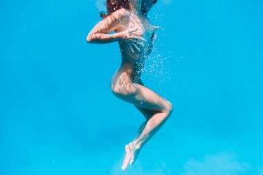 Su altında mavi okyanusta yüzen güzel çıplak kadın